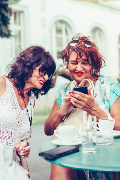 istock Cheerful senior ladies using a smart phone, laughing and talking while sitting outdoors 1177339725