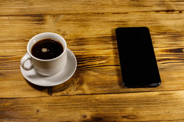 istock Cup of coffee and smartphone on a wooden table 1177341459