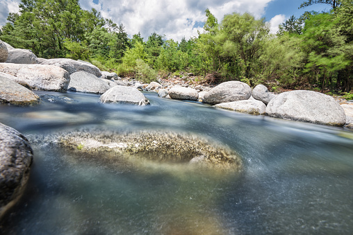 Long exposure with strong 64x nd-filter picture at daytime. Photography of the flowing river Maggia in Switzerland. Wilderness and lonely landscape that can be explored with outdoor activities.