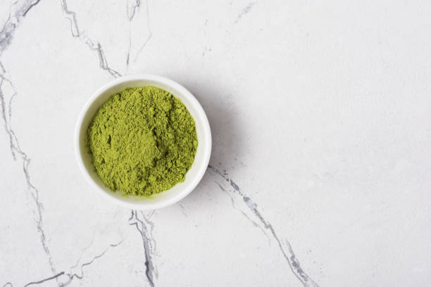 Green matcha tea powder in bowl Top view of organic green matcha tea powder in bowl on white marble background with copy space matcha tea photos stock pictures, royalty-free photos & images