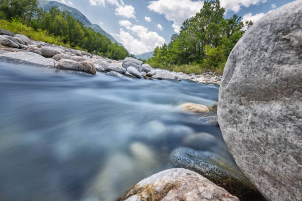 Long exposure with strong 64x nd-filter picture at daytime. Photography of the flowing river Maggia in Switzerland. Wilderness and lonely landscape that can be explored with outdoor activities.