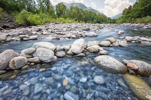 Long exposure with strong 64x nd-filter picture at daytime. Photography of the flowing river Maggia in Switzerland. Wilderness and lonely landscape that can be explored with outdoor activities.