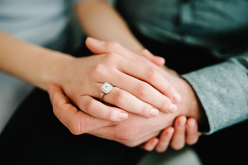 Close up of an elegant engagement diamond ring on woman finger. love and wedding concept.