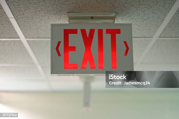An Exit Sign Hanging From A Ceiling Stock Photo - Download Image Now - Exit Sign, Red, Emergency Sign