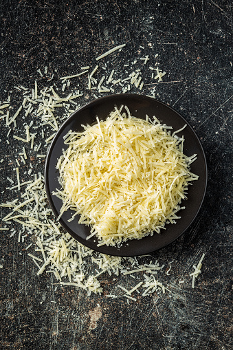 Tasty grated cheese. Parmesan cheese on old kitchen table. Top view.