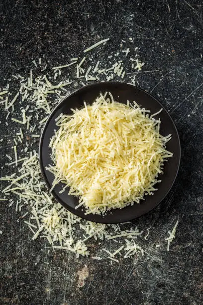 Tasty grated cheese. Parmesan cheese on old kitchen table. Top view.