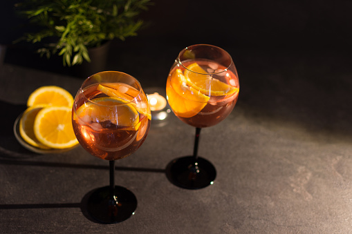 Two glasses of italian Spritz cocktail with orange slices on black background.