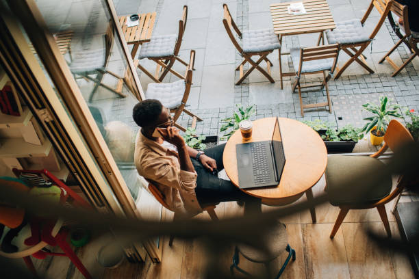 Young African man sitting in coffee shop and using laptop
