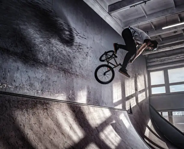 Young BMX making crazy tricks on his bicycle in skatepark indoors. Bmx freestyle.