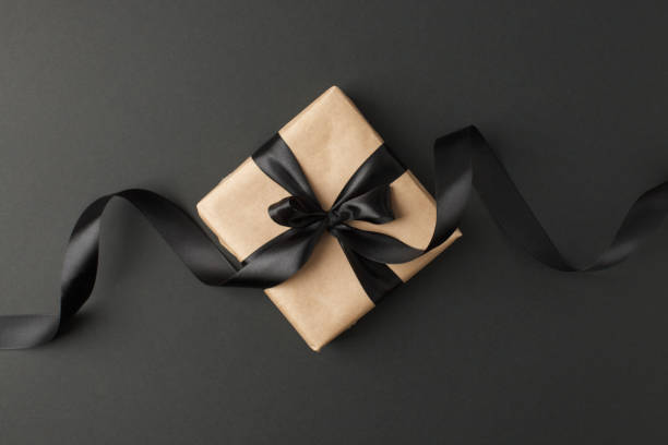 istock Craft gift box on a dark background, decorated with a textured bow and feathers, creating a romantic luxury atmosphere. For birthday, anniversary presents, gift post cards. 1177377768