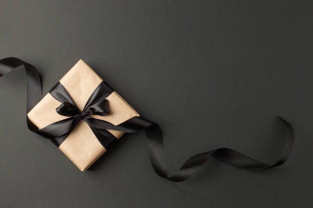istock Craft gift box on a dark background, decorated with a textured bow and feathers, creating a romantic luxury atmosphere. For birthday, anniversary presents, gift post cards. 1177377804