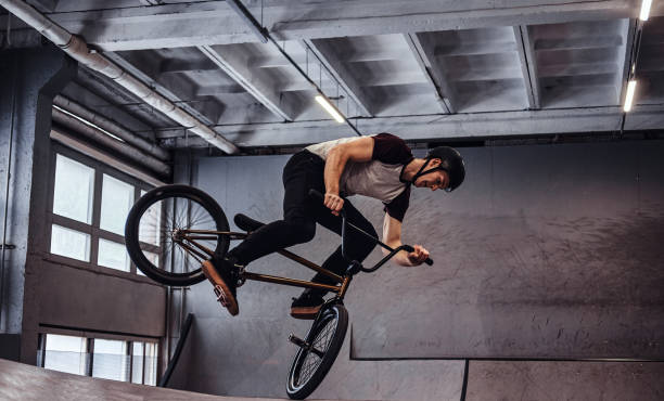 istock Young man with BMX performing tricks in skatepark indoors 1177377943