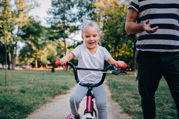 istock Little Girl Learning To Ride Bicycle With Her Dad 1177377947