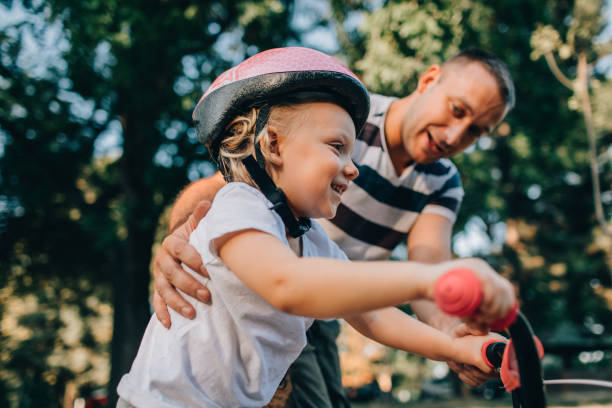 istock Little Girl Learning To Ride Bicycle With Her Dad 1177377985