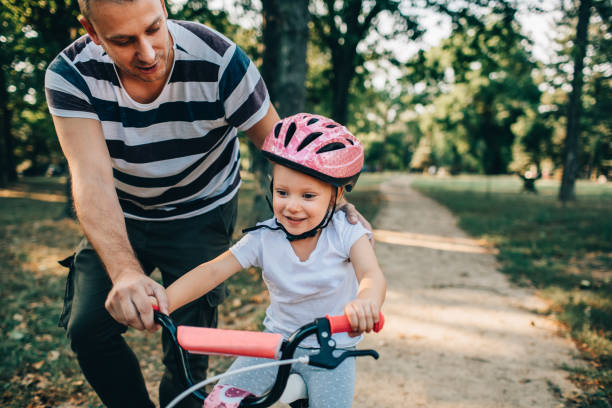 istock Little Girl Learning To Ride Bicycle With Her Dad 1177378021