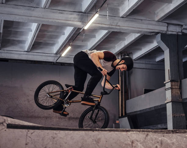 istock Young man with BMX performing tricks in skatepark indoors 1177378043