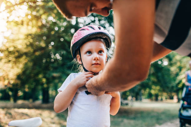 He's My Hero Father adjusting helmet to his little daughter and she looking at him. cycling helmet photos stock pictures, royalty-free photos & images
