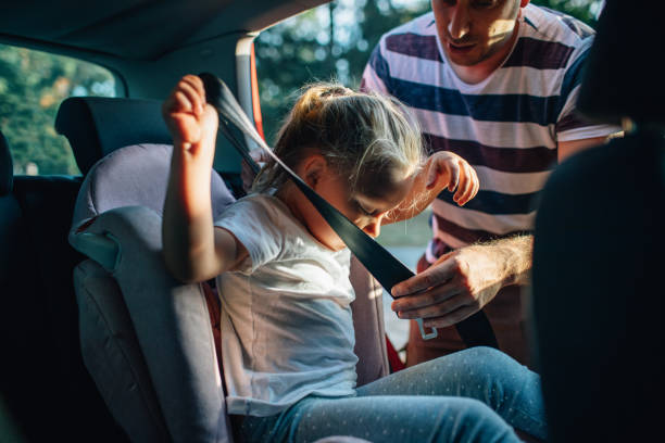 Commuting By Car Father putting daughter into car seat. seat belt stock pictures, royalty-free photos & images