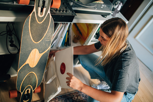 Young Female DJ choosing records at home for performance.