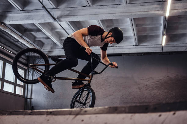 istock Young man with BMX performing tricks in skatepark indoors 1177378305