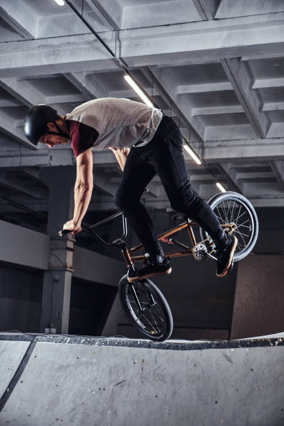 istock Young man with BMX performing tricks in skatepark indoors 1177378434