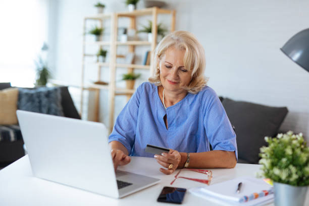 istock Smiling senior woman shopping online using laptop 1177379813