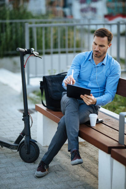 istock Businessman using digital tablet in the city park after scooter riding 1177380822