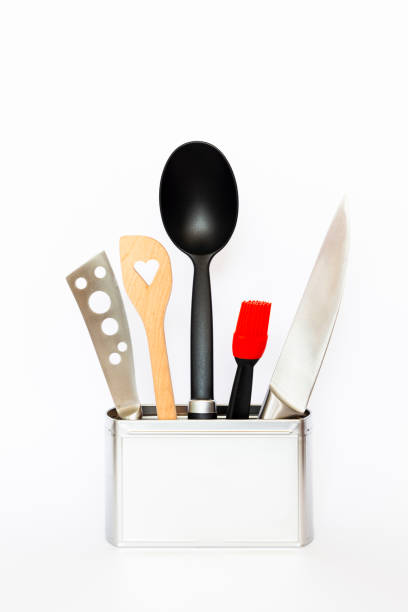 Assortment of kitchenware and cooking tools in a square silver colored metal box with copy space on white background