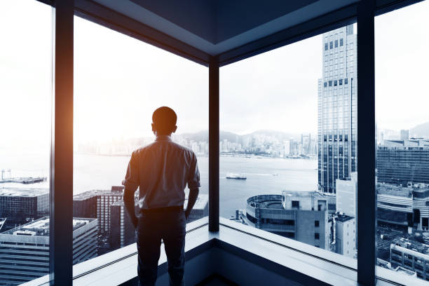 Businessman looking at city through office window