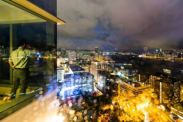 Businessman standing by the window and using phone at night.