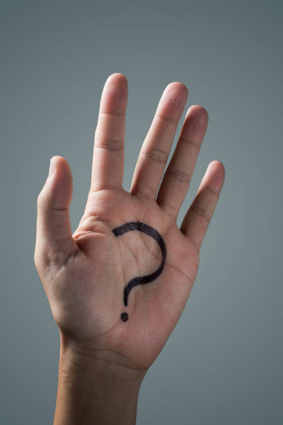man with a question mark painted in the palm of his hand on an off-white background