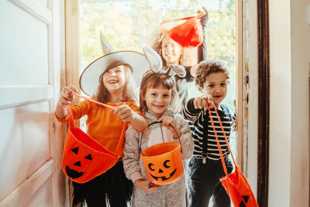 kinder in halloween-kostümen vor einem alten haus - trick or treat stock-fotos und bilder