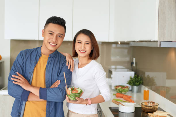 istock Beautiful young couple is looking at each other and smiling while cooking in kitchen at home. 1177390934