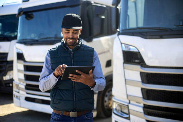 Truck driver using a tablet Truck driver using a tablet. About 35 years old, African male. trucking stock pictures, royalty-free photos & images