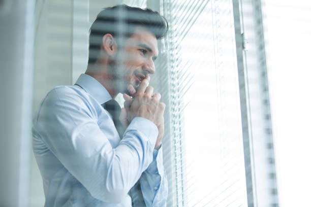 istock Businessman looking through window shades in the office 1177394881