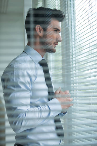 istock Pensive man looking through window in his office 1177394891