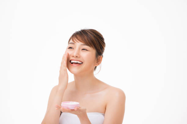 Beauty concept. Asian girl is applying cream on her face. Beauty concept. Asian girl is applying cream on her face. vietnamese girls for sale stock pictures, royalty-free photos & images