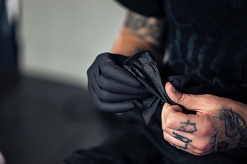 Artista de tatuajes poniéndose guantes de protección photo