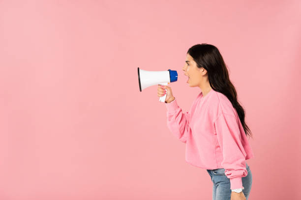 istock beautiful girl yelling into megaphone, isolated on pink 1177399095