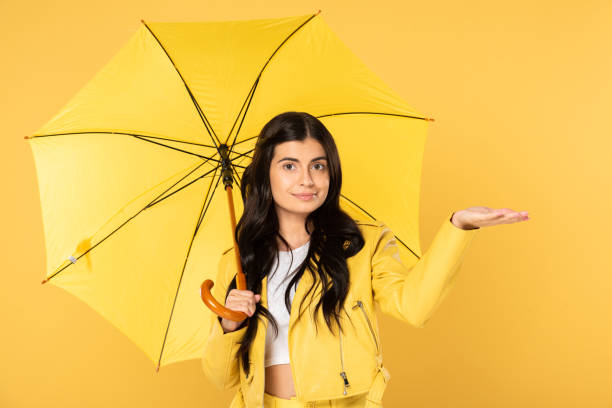 istock attractive girl posing with umbrella, isolated on yellow 1177399100