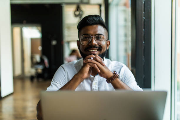 istock Indian man using laptop computer while drinking a cup hot milk tea, outdoor cafe. 1177401138