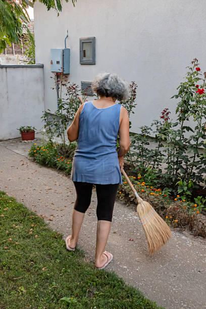 istock Senior Woman is Sweeping the Backyard with Broom 1177401779