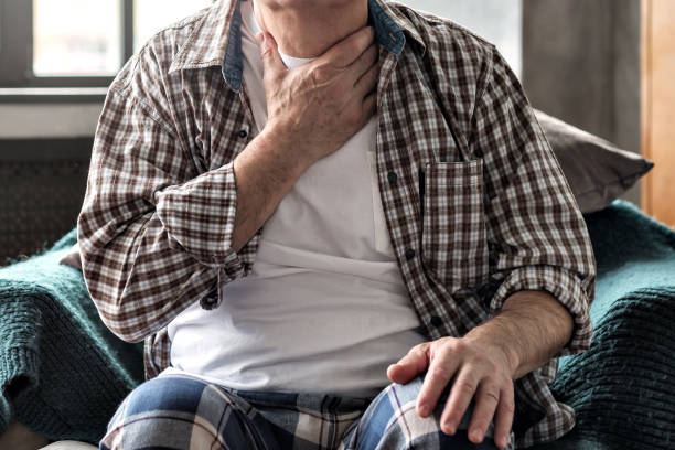 senior man with throat pain sitting on sofa. - russian influenza epidemic virus flu virus imagens e fotografias de stock