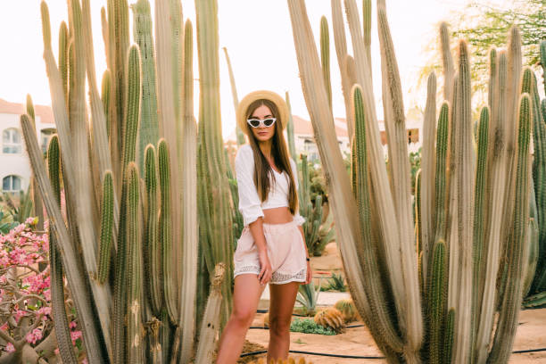 istock Young girl in hat and sunglasses posing against cactuses 1177409449