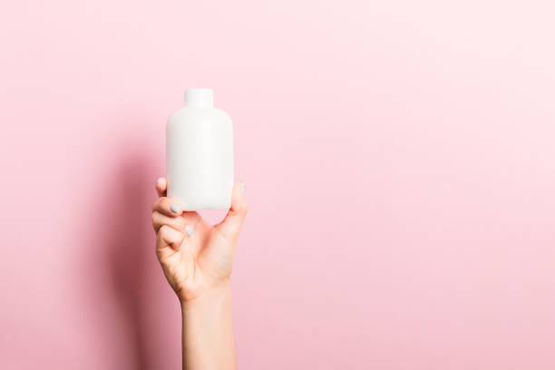 Female hand holding cream bottle of lotion isolated. Girl give tube cosmetic products on pink background Female hand holding cream bottle of lotion isolated. Girl give tube cosmetic products on pink background. beautiful women giving head stock pictures, royalty-free photos & images