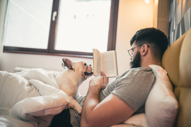 istock Man reading book in the bed, cuddling with his dog 1177416615