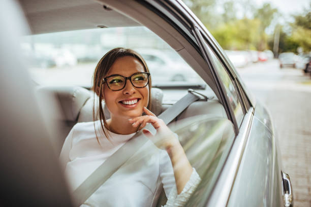 窓の外を見ている車の後部座席に幸せな若い女性の肖像画。 - タクシー ストックフォトと画像