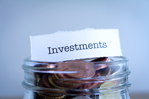A close-up shot of the word Investments on a jar of coins.