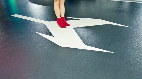 Woman standing on white direction arrow.