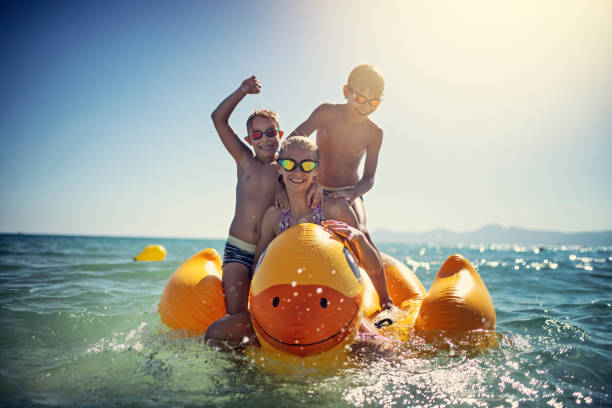 istock Kids enjoying riding a giant duck on sea. 1177421355
